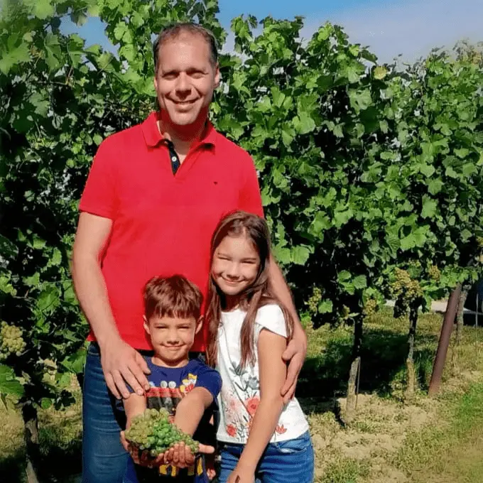 Reinhold Wagner steht mit seinen Kindern vor einem Hintergrund aus Weintrauben